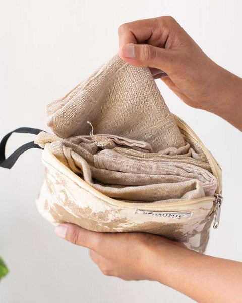 Hand holding an eco-friendly Package-Free Kit pouch with reusable cotton produce bags inside sustainable shopping bag set NZ.